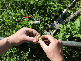 male hands making connection of parts in garden irrigation structure, close-up, adjustment of...
