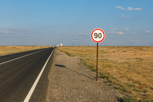speed limit sign indicates 90 km along a vast road in Atyrau Region, Kazakhstan