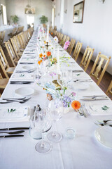 Banquet table in rustic European style. White tablecloth and empty glasses and plates..