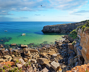 Rocky coastline,  ocean and sunlight shines through gaps in clouds. Beautiful nature background.