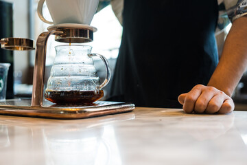 Alternative coffee brewing method, using pour over dripper and paper filter. Barista making a drip coffee