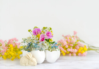 Beautiful composition with flowers in eggs shells and easter bunny figurine on table. festive spring season. decor for Easter holiday, Ostara sabbat.