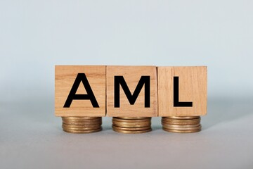 AML text on a wooden block with stacked coins. Anti-money laundering (AML) concept 