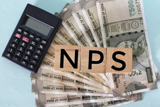 NPS or national pension scheme with wooden bids or blocks on Indian rupees notes.