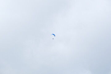 Parapente bleu dans un ciel blanc bleu clair nuageux