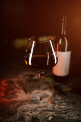 Rich red wine in a glass next to an elegant bottle on a dark textured surface