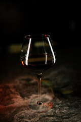 Elegant wine glass sits on a textured surface illuminated by soft lighting in a dim setting