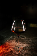 Red wine glass placed on a textured surface with ambient lighting in a dimly lit setting during evening hours