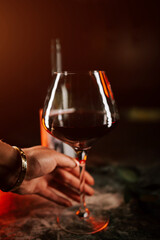 Evening gathering with a glass of red wine held in hand against a warm, inviting backdrop