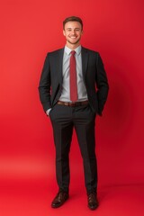 Portrait of a successful smiling young business man dressed in a suit. Studio shot against a vivid red background.