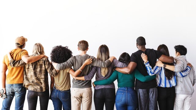 Diverse group of people standing hugging, embracing each other facing away. Unity and diversity. Mixed ethnicities, men and women, embracing diversity and togetherness.