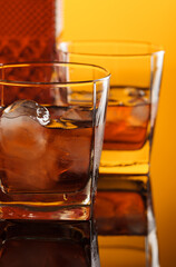 Whiskey with ice on a reflective background.