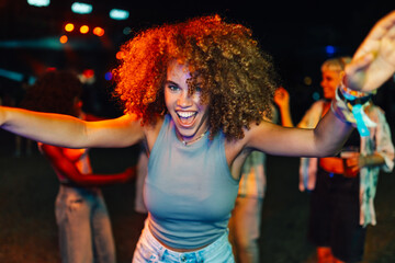 Young woman dancing and enjoying live music at night concert