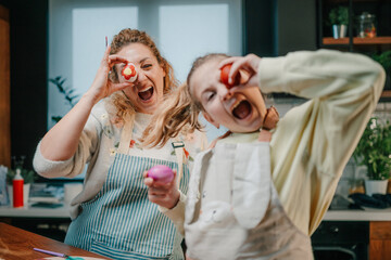 Fototapeta premium Mother and daughter having fun painting easter eggs in the kitchen