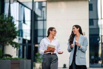 Two businesswomen walking and talking outside the office building