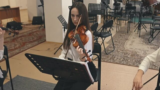 A female musician gracefully plays the violin, her fingers moving precisely on the strings. The violin resonates with rich tones, showcasing the beauty of classical music and skilled artistry