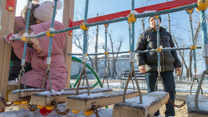 Grandfather with grandchildren playing on the playground on a cold winter day