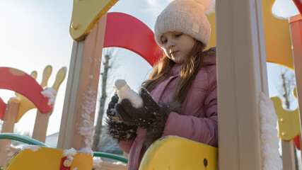 little girl playing on the playground on a winter day