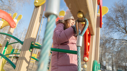 little girl playing on the playground on a winter day