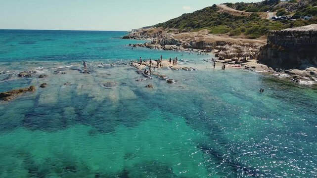 Rocky seacoast aerial view from Tigania Beach in Greece. Sithonia beach with clear waters and tourists enjoying the trip.