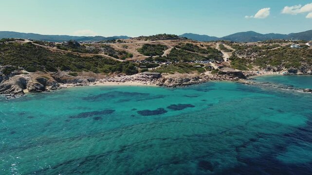 Sithonia Greece shot of Tigania beach coastline with tourists on vacation. Summer scenic vacation on Greep peninsula with extreme clear water.