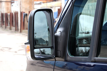 Cargo van side mirror with reflection in it. Black Rear-view mirror on a cargo van. Left external...