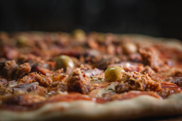 Close up of a savory pizza topped with meat and green olives.