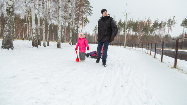 Father and daughters ride downhill on a Snow tubing in the park on the winter holidays