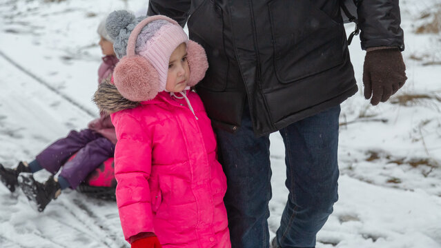 Father and daughters ride downhill on a Snow tubing in the park on the winter holidays