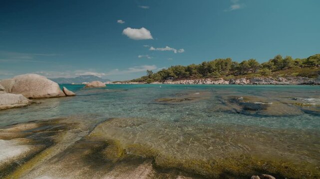 Mediterranean Sea coast with rocky under expansive cloudscape. Greek coastal landscape under bright summer sky.