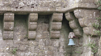 Mont-Saint-Michel: rusty small bell among the corbels of a parapet wall, bulwark on the north slope...