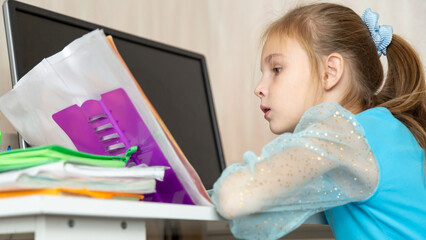 Little school girl sit at table at home write in exercise book prepare homework alone.