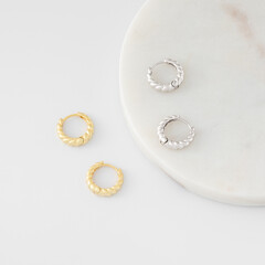 Stylish gold and silver hoop earrings are on white. Catalog of jewelry