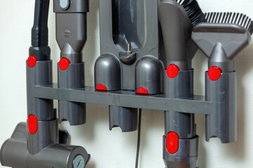 Wall mounted vacuum cleaner charging and storing station with various accessories hanging and...