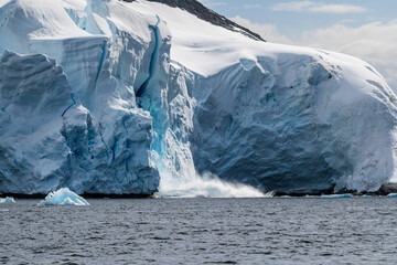 Telephoto of a giant chunk of ice calving off an ice sheet. Graham Passage, near Charlotte Bay, on...
