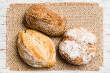 Assortment of freshly baked bread with napkin on rustic table top view. Healthy unleavened bread. French bread