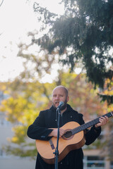 Fototapeta premium Musician singing and playing acoustic guitar outdoors in autumn