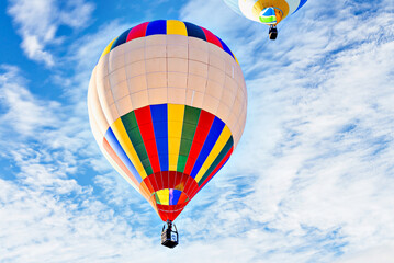 Colorful hot air balloon flying over blue sky with white clouds	