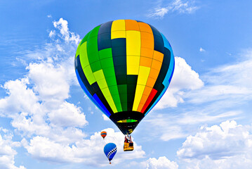 Fototapeta premium Colorful hot air balloon flying over blue sky with white clouds 