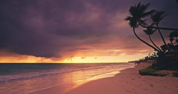 Color ocean sunrise, tropical island beach shore with palm trees and ripple water waves on the sand. Caribbean islands.