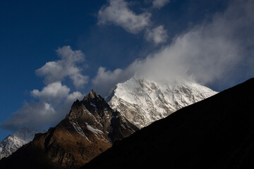 A mountain covered in snow with a cloud in the sky