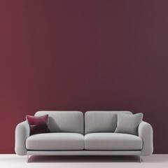 Modern gray sofa with plush burgundy pillow in front of a deep red wall