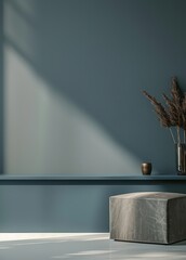 A minimalist interior design scene with a blue wall. a gray ottoman. and a vase with dried flowers