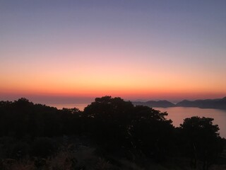 A vibrantly coloured sky during sunset over the mountains and sea 