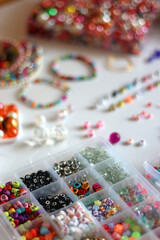 Friendship bracelet spelled with letter beads. Colorful handmade bracelets and various jewelry making supplies. Selective focus, white background.