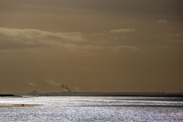 Sunlight on River Dee estuary with industrial architecture of north Wales on horizon