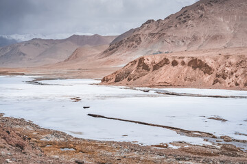 Snow lies in the valley in the highlands of Tien Shan in Pamir in Tajikistan, panoramic landscape for background in high mountains with rocks, snow and glaciers