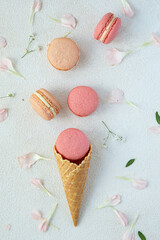 French rose macarons on light background in ice cream waffle cones, perfect for st Valentine's day and mother's day, Flat lay, with green leaves and flowers 