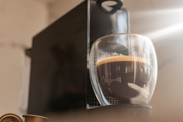 Espresso brewing in a modern coffee maker during a sunny morning at home