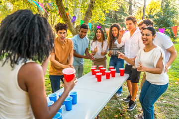 African woman about to throw the ball playing beer pong with friends in a park